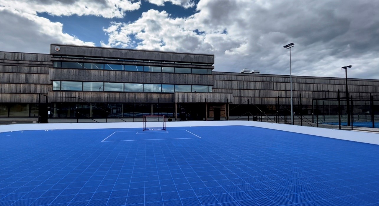 Aktivitetsyta utomhus med innebandymål och blått golv utanför Knivsta Centrum för idrott och kultur 