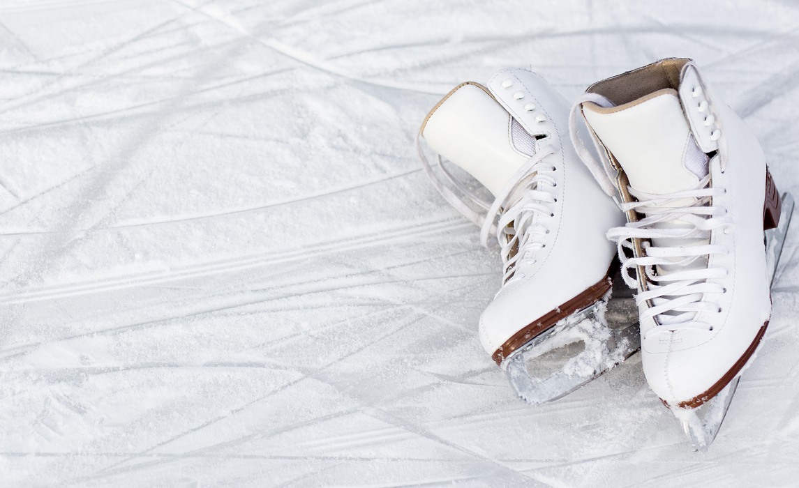 close up of white figure skates and copy space over ice background with marks from skating or hockey